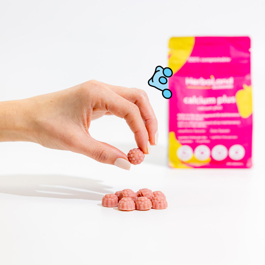 Person holding herbaland gummies, with calcium plus pouch for maintaining healthy bones and teeth for adults with strawberry banana flavor for adults in the background
