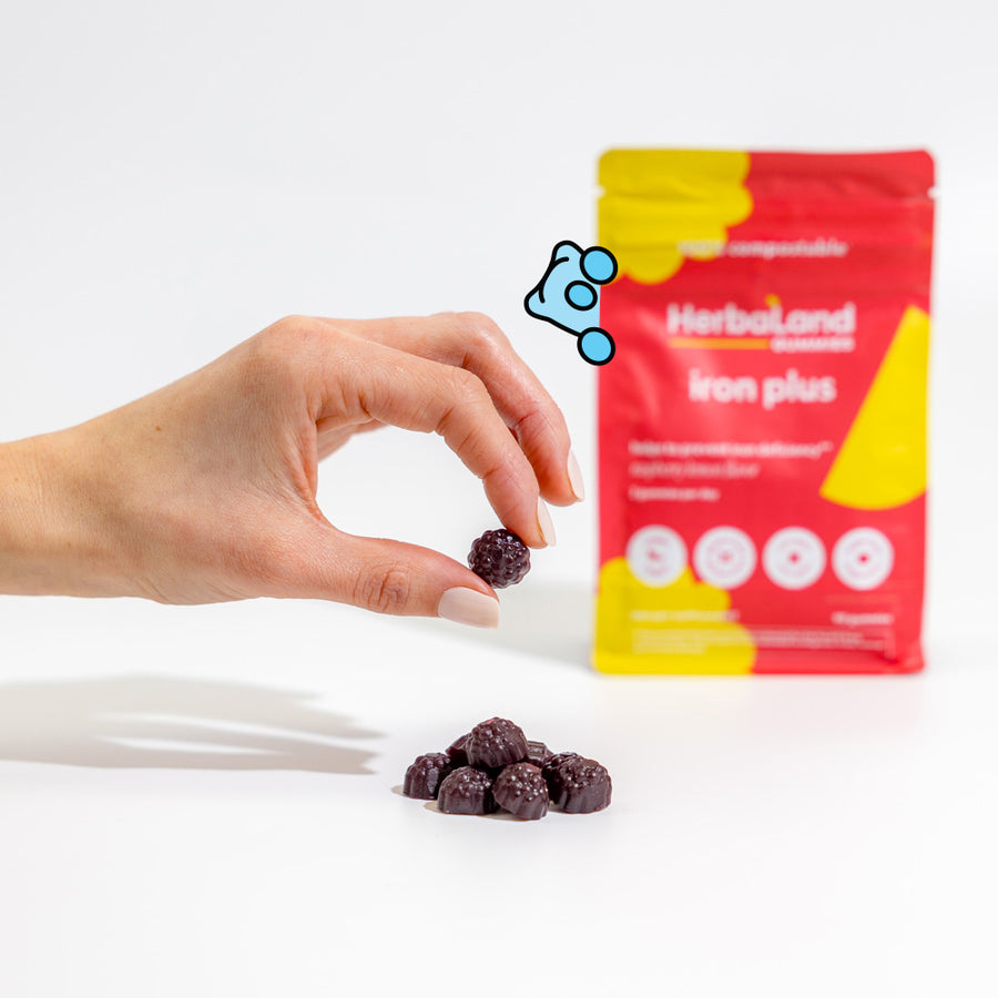 Person holding herbaland gummies, with iron plus pouch to help to prevent iron deficiency for adults with raspberry lemon flavor